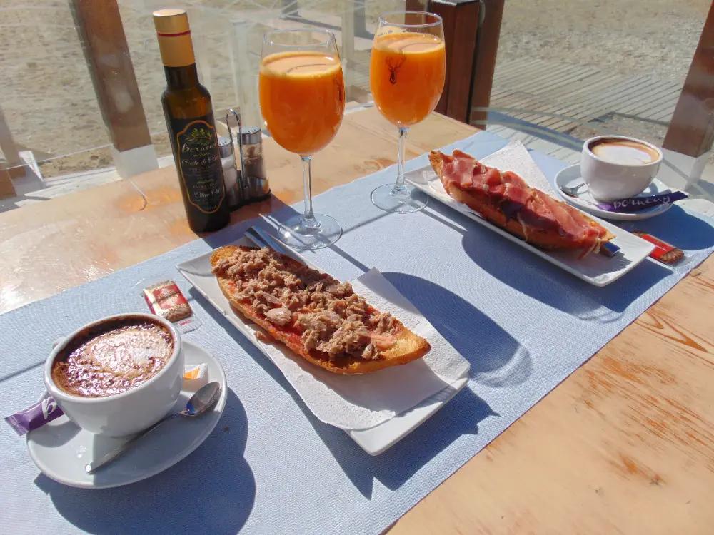 Desayuno con café, zumo y tostadas de atún y jamón