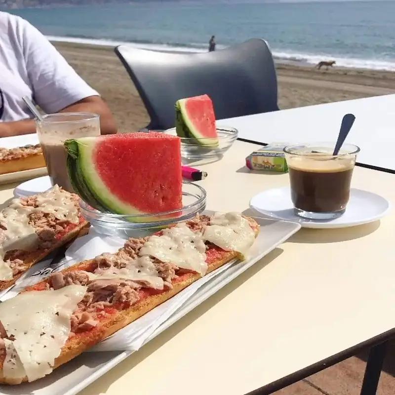 Desayuno de tostadas de atún, tomate, queso, sandía y café